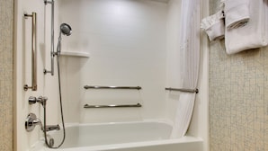 A modern bathroom with a walk-in bathtub, grab bars, and a showerhead.