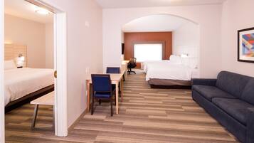 A hotel room with a bed, a sofa, a desk, and a chair.