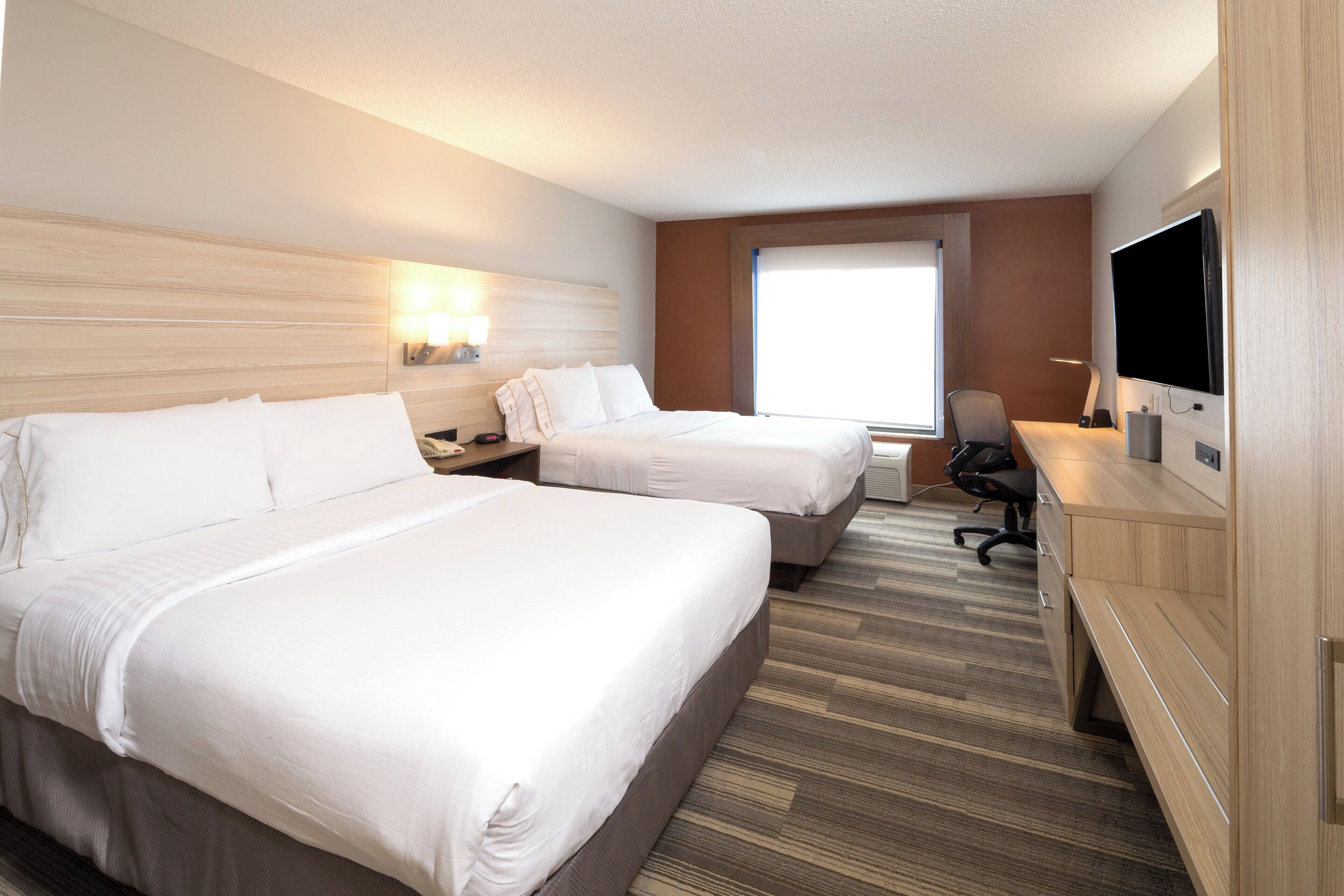 Une chambre d’hôtel avec deux lits, un bureau, une télévision et une fenêtre.