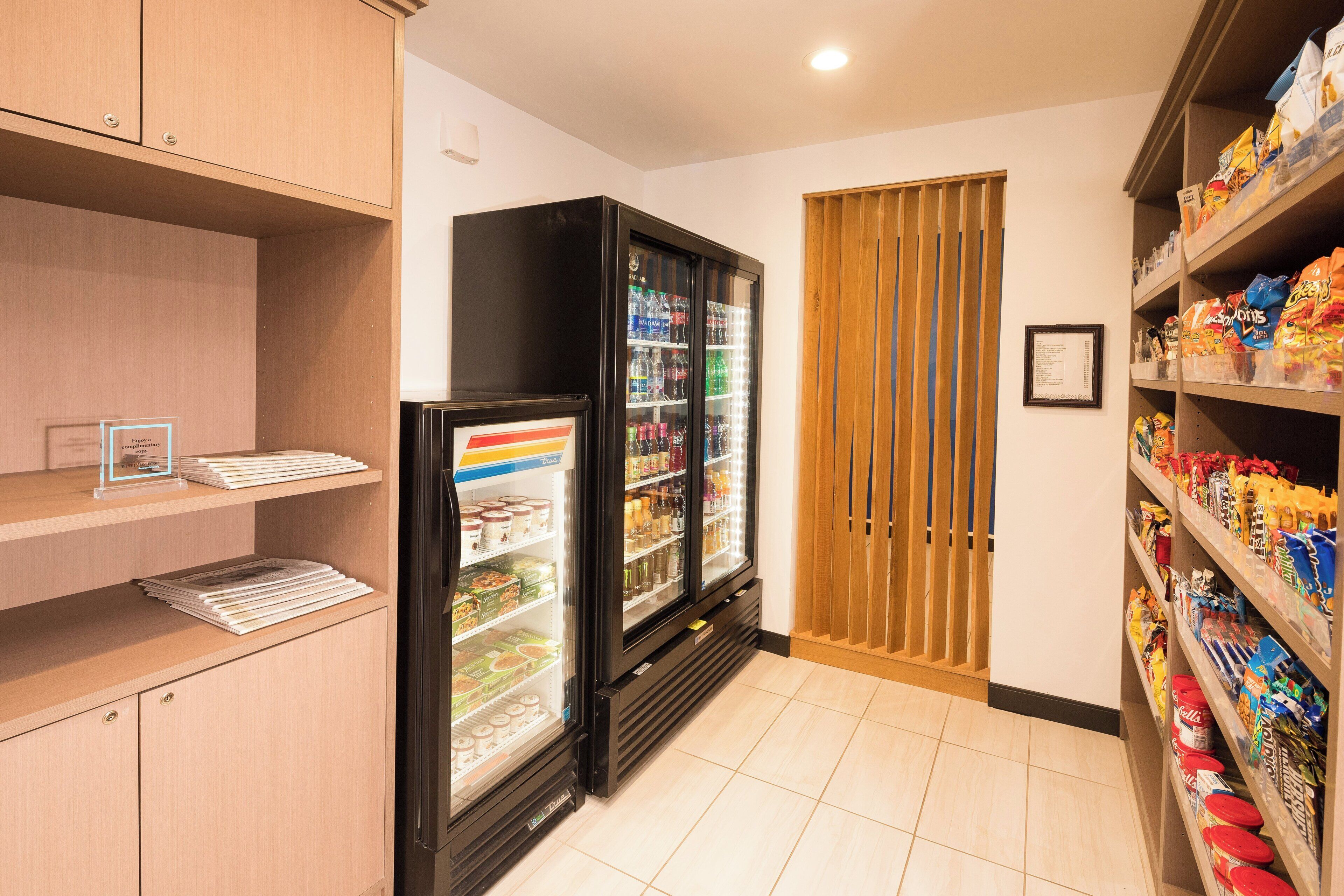 A hotel room with a minibar, a refrigerator stocked with beverages, and shelves with snacks.