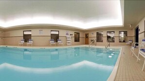 An indoor swimming pool with clear water, surrounded by tiled walls and a tiled floor. There are several lounge chairs and a pool ladder visible. - Holiday Inn Express Hotel & Suites Grand Blanc by IHG (Grand Blanc)