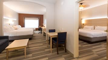 A hotel room with two beds, a desk, a chair, and a sofa.