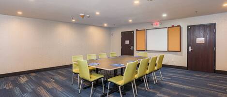 A conference room with a long table, yellow chairs, and a carpeted floor.