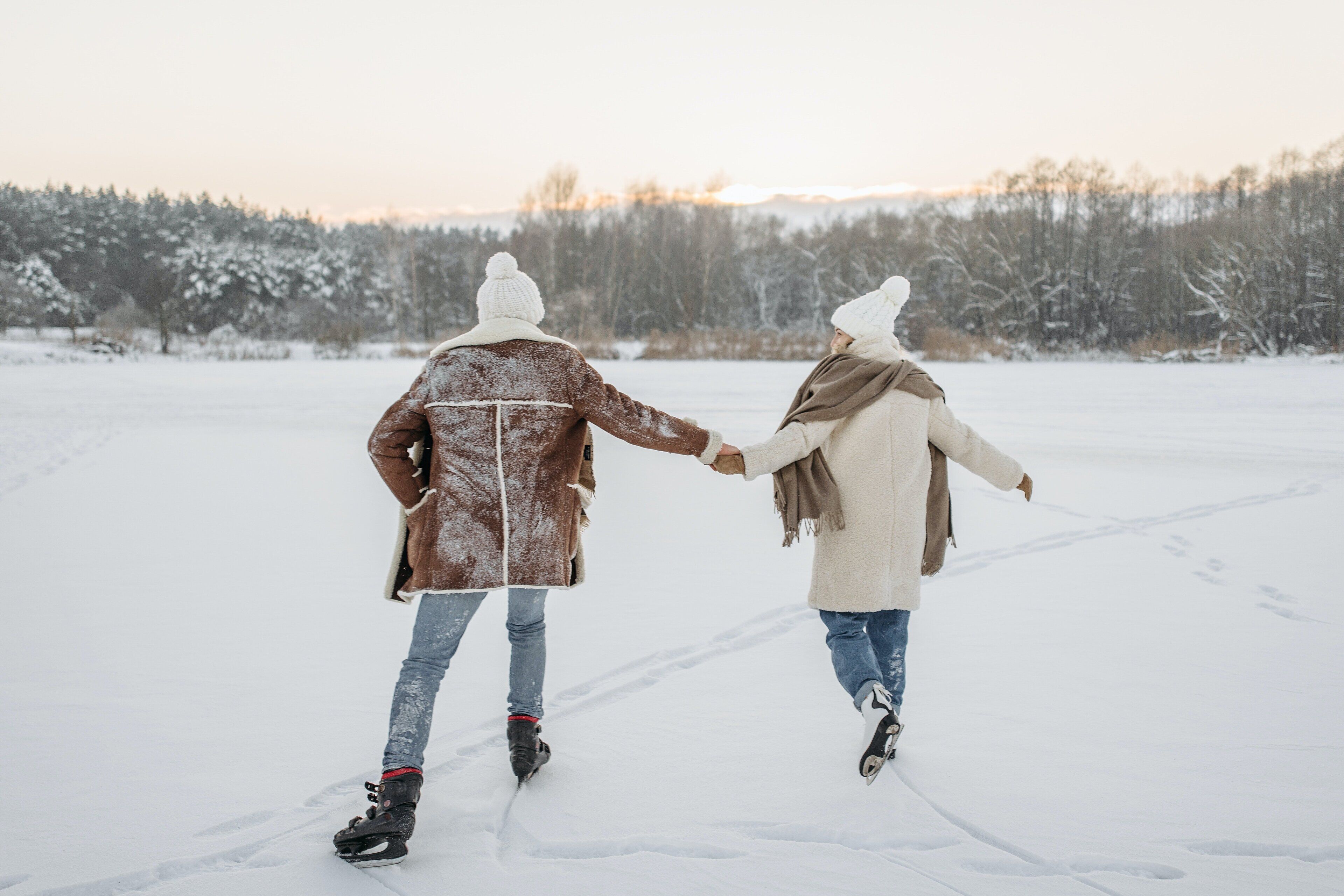 Two people walking on a snowy path, holding hands.