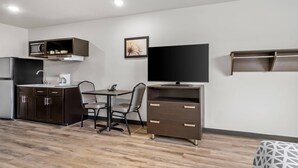 Eine moderne Küche mit Mikrowelle, Herd und Spüle, ein Essbereich mit Tisch und Stühlen sowie ein an der Wand befestigter Fernseher.