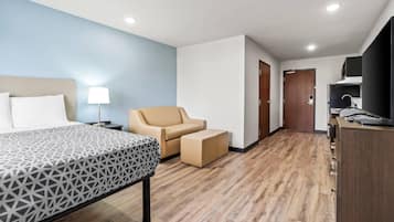 A hotel room with a bed, a chair, a desk, and a wardrobe.