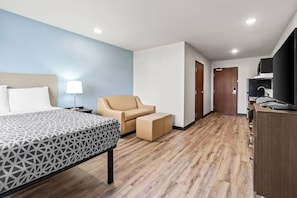 Une chambre d’hôtel avec un lit, une chaise, un bureau et une armoire.