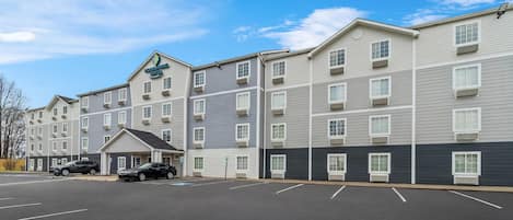 A multi-story hotel with a parking lot and two cars parked.
