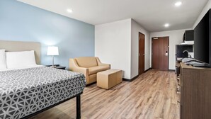 Ein Hotelzimmer mit Bett, Sessel, Schreibtisch und Kleiderschrank.