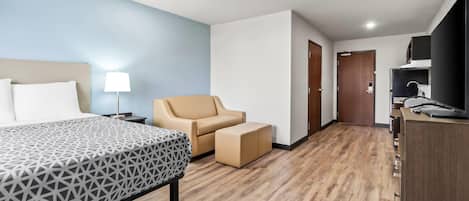 A hotel room with a bed, a chair, a desk, and a wardrobe.