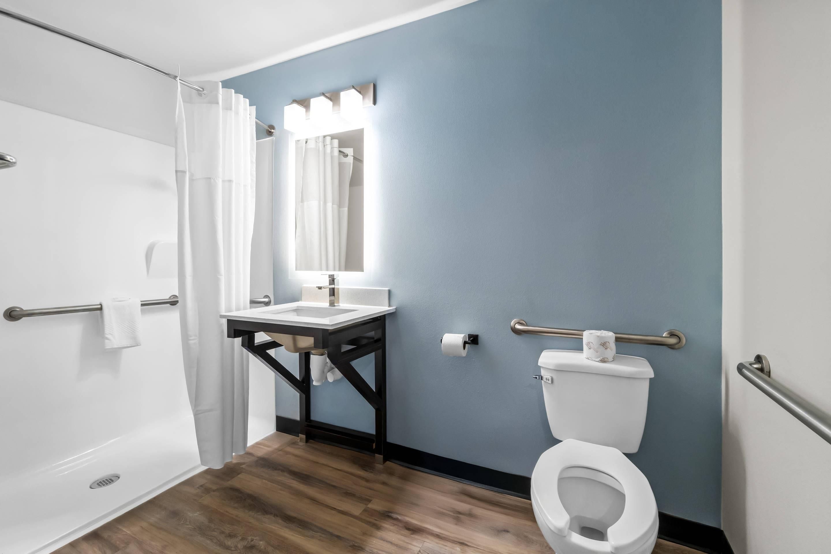 Une salle de bain équipée d’une douche, d’un lavabo, de toilettes et d’un miroir avec éclairage.