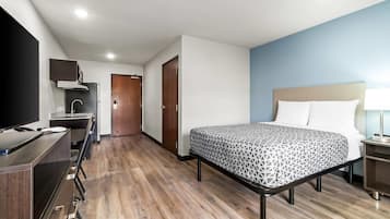 Una camera d'albergo con un letto, una scrivania, una televisione, un armadio e un bagno.