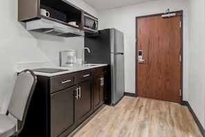 Eine kleine Küche mit Mikrowelle, Kaffeemaschine und Kühlschrank.