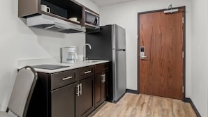 Eine kleine Küche mit Mikrowelle, Kaffeemaschine und Kühlschrank.