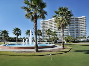 A hotel with a pool, palm trees, and a golf course.