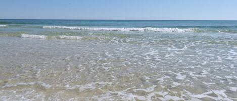 A beach with clear water and gentle waves.