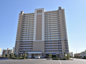 Ein hohes, mehrstöckiges Hotel mit zentralem Eingang und Parkplatz.