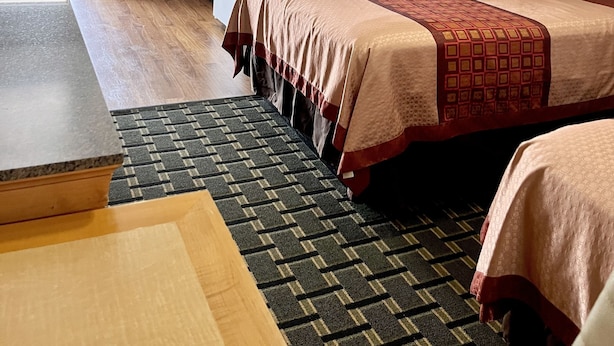 A compact hotel room with a kitchenette, a bed with a patterned bedspread, and a small sitting area with a table and chair. - Chief Motel (Keokuk)