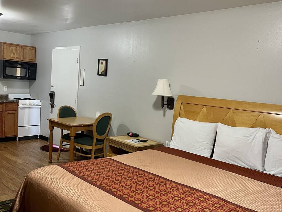 Habitación de hotel con una cama, un escritorio con silla, microondas, estufa y refrigerador.