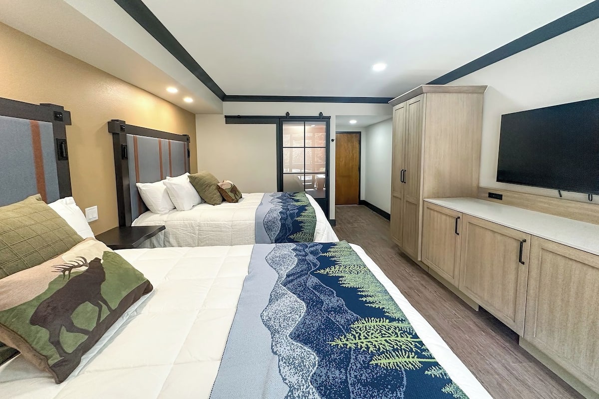 A hotel room with two beds, a TV, and a wardrobe.