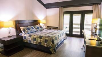 A hotel room with a bed, bedside tables, a desk, and a view through a glass door.