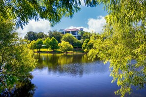A house with a red roof, surrounded by trees and a lake. - Caribe Cove Resort (Kissimmee)