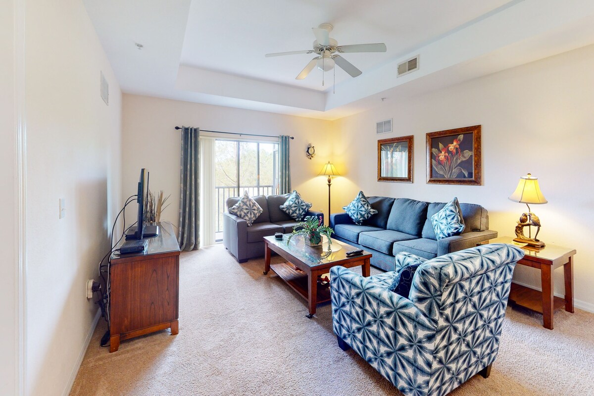 A living room with a sofa, armchair, coffee table, and a television on a wooden cabinet.
