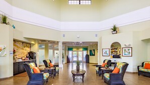 A spacious lobby with a high ceiling, comfortable seating areas, a reception desk, and a large map on the wall. - Caribe Cove Resort (Kissimmee)