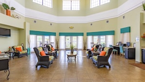 A spacious lobby with high ceilings, multiple seating areas, and large windows allowing natural light. - Caribe Cove Resort (Kissimmee)