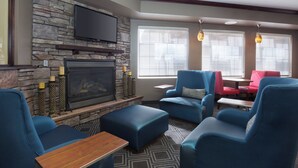 A modern living room with a stone fireplace, blue seating, and a flat-screen TV. - TownePlace Suites by Marriott Pocatello (Pocatello)