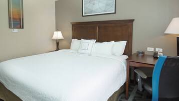 Een hotelkamer met een groot bed, een bureau met stoel, een lamp en een schilderij aan de muur.