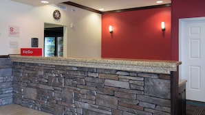 A reception area with a stone wall, a 'Hello' sign, a clock, and a refrigerator. - TownePlace Suites by Marriott Pocatello (Pocatello)