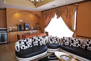 A living room with a sofa set, a coffee machine, and a dining area.
