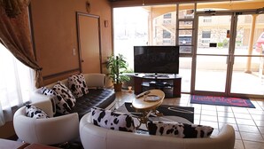 A living room with a sofa, armchairs, a coffee table, a TV, and a potted plant.