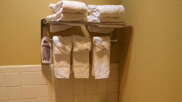 Un baño con inodoro, toallero con toallas dobladas y soporte para papel higiénico.