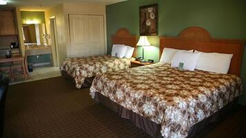 A hotel room with two beds, a desk, and a mirror.