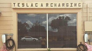Un edificio con un letrero que dice "TESLA CHARGING" sobre una ventana.