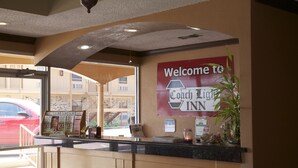 Una recepción con un cartel de bienvenida para Coach Light Inn, una barra con revistas y vistas al exterior.