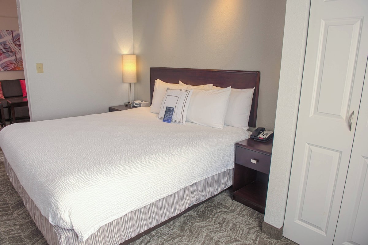 A neatly made bed with a headboard, a bedside lamp, and a telephone on the nightstand.