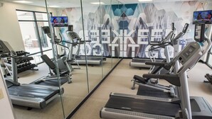 Ein Fitnessstudio mit Laufbändern, Krafttrainingsgeräten und einer Spiegelwand.