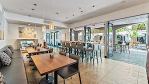 A modern dining area with long tables, chairs, and hanging pendant lights.
