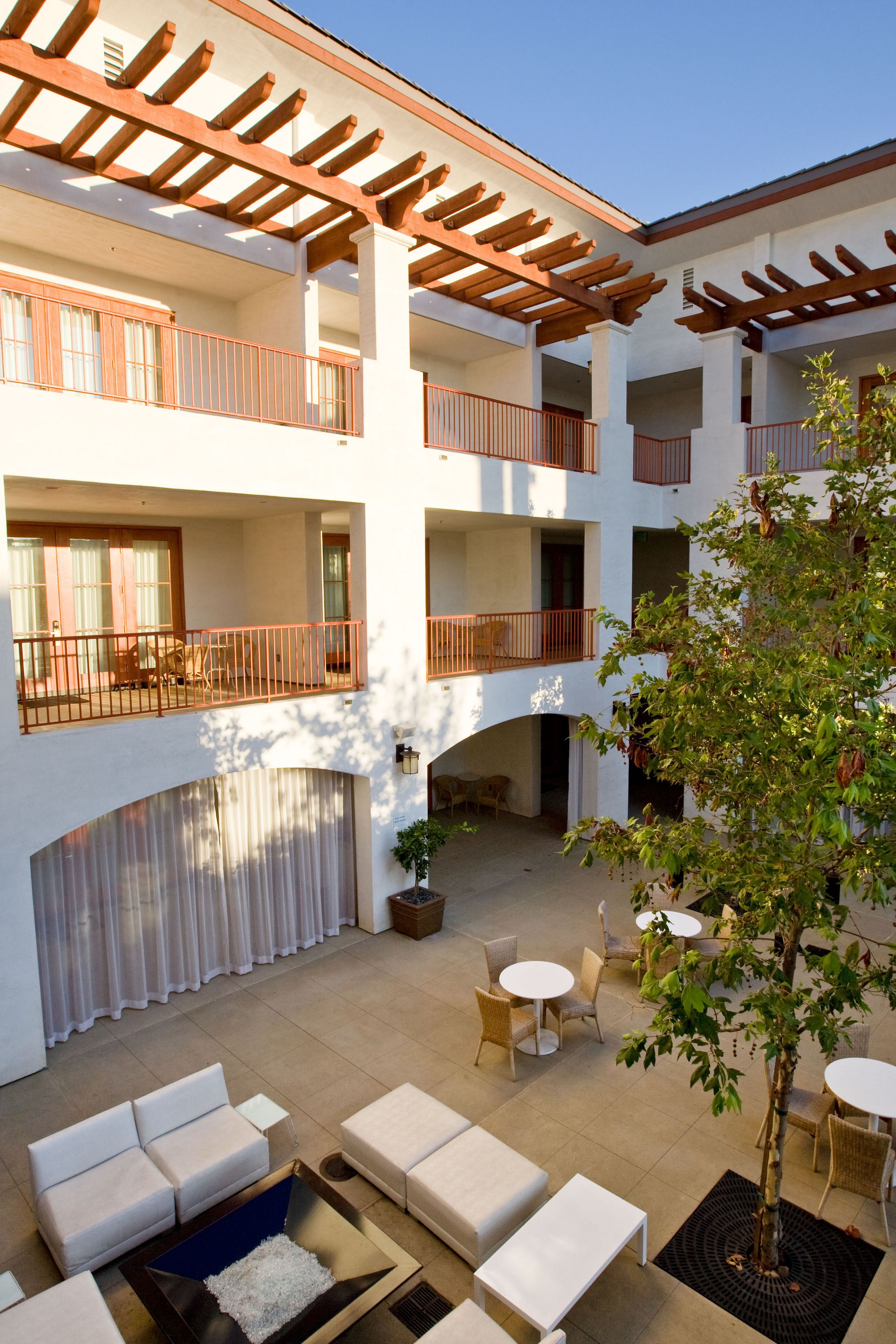 A multi-level outdoor patio with seating areas, a pergola, and a tree.