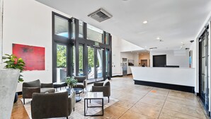 A spacious lobby with a reception desk, seating area, and large windows offering views of greenery.