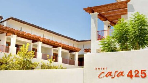 A hotel named 'casa 425' with a white facade, wooden balconies, and green plants.