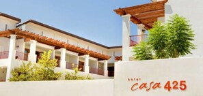 Un hotel llamado 'casa 425' con fachada blanca, balcones de madera y plantas verdes.