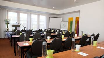 Un salón de conferencias con varias mesas, sillas y una pizarra.