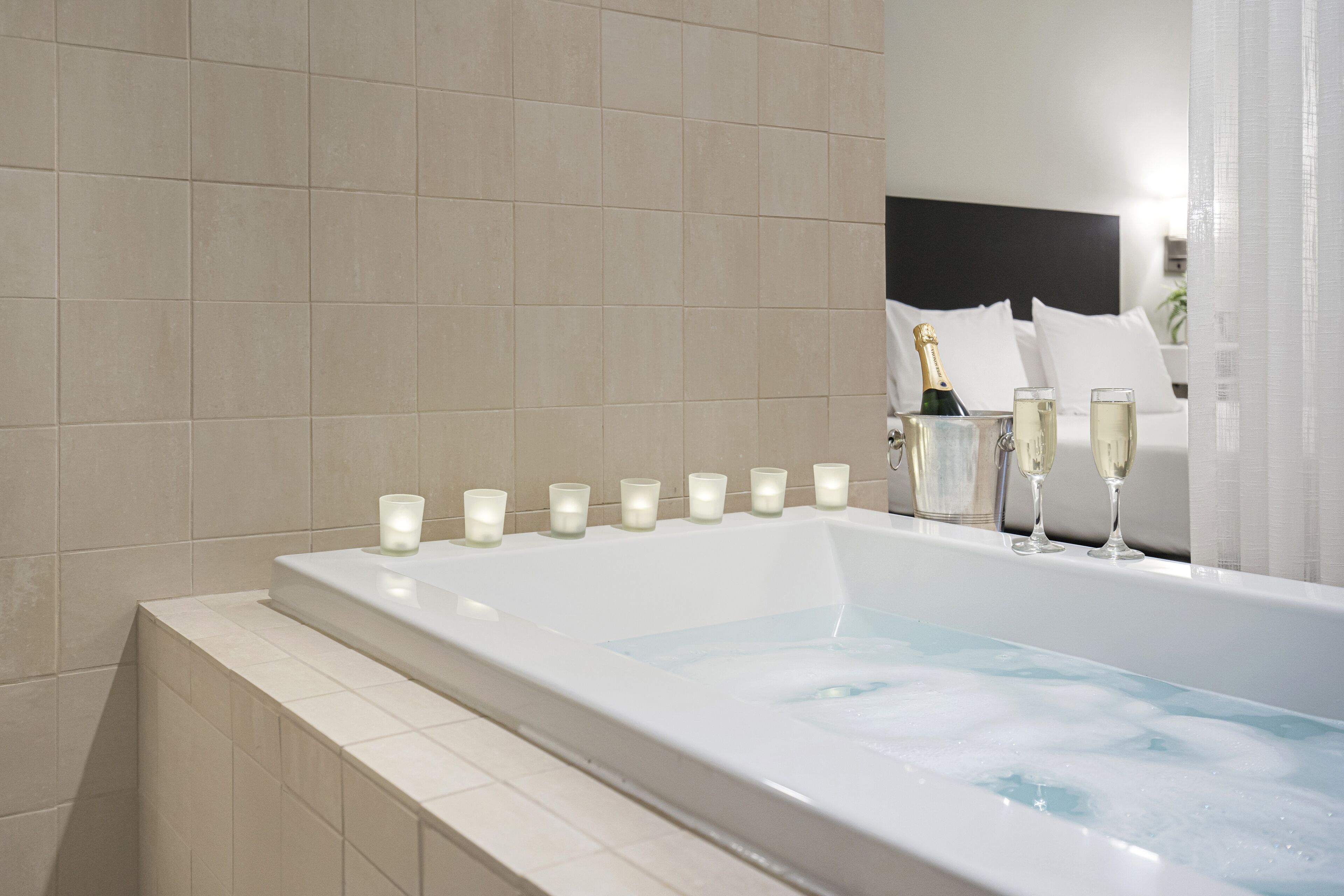 Une salle de bain moderne avec une grande baignoire, des bougies et des coupes à champagne.