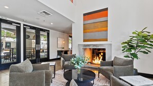 A modern lounge area with a fireplace, comfortable seating, and a view of the outdoor patio.