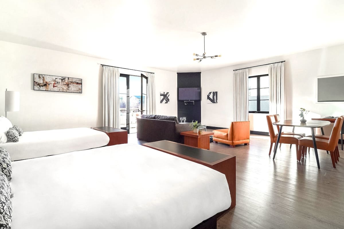 Habitación de hotel con una cama grande, un sofá, una mesa de comedor con sillas y un televisor.