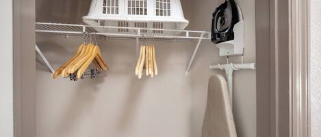 A laundry area with a drying rack, a drying machine, and wooden hangers hanging on a wall-mounted rack.